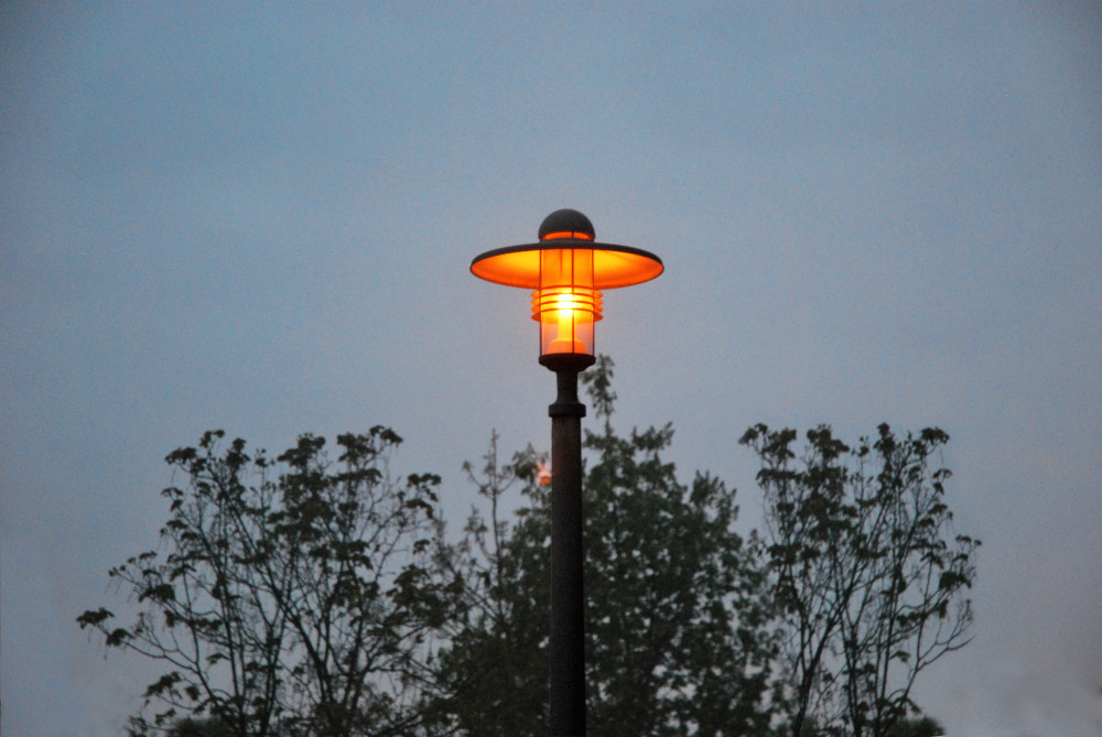 Eine Straßenlaterne leuchtet im Morgengrauen